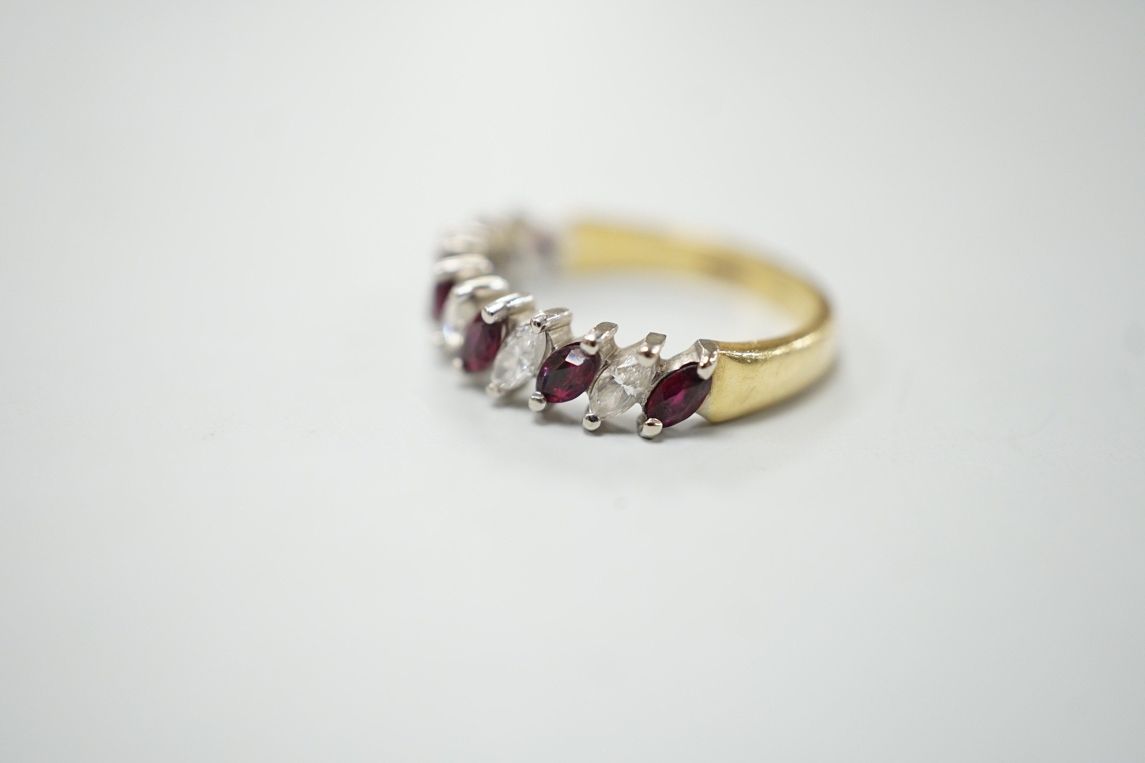 A modern 18ct gold and eleven stone marquise cut ruby and diamond set half hoop ring, size L, gross weight 3.5 grams.